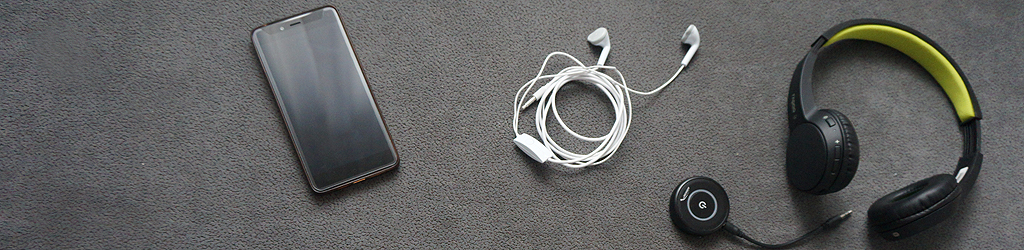 telefon, słuchawki do uszu i słuchawki bezprzewodowe leżą na kanapie