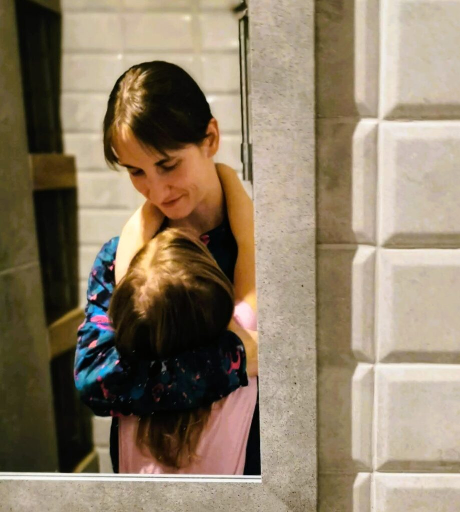 Matka (Justyna) przytula dziecko - wszystko widoczne w odbiciu w lustrze